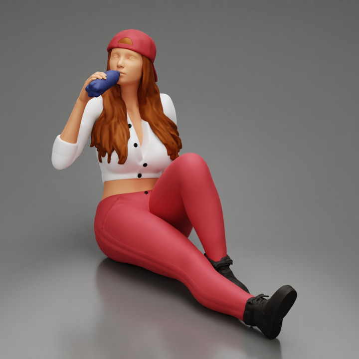 Tired woman mechanic in shirt pants and backwards cap sitting and drinking water during from bottle image