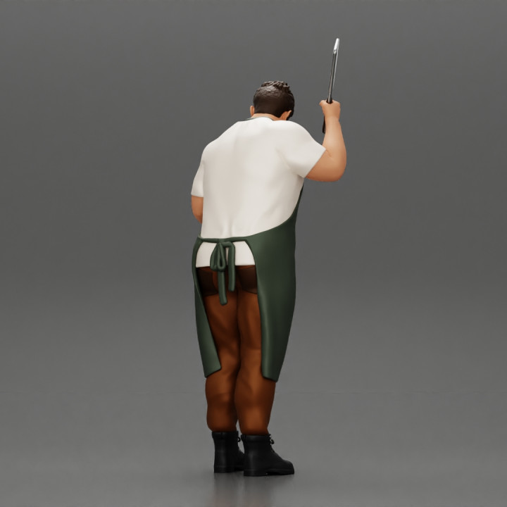butcher standing while holding a cleaver and cutting something image