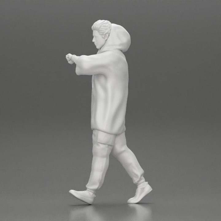 Man in a long hoodie  walking and looking at his watch image