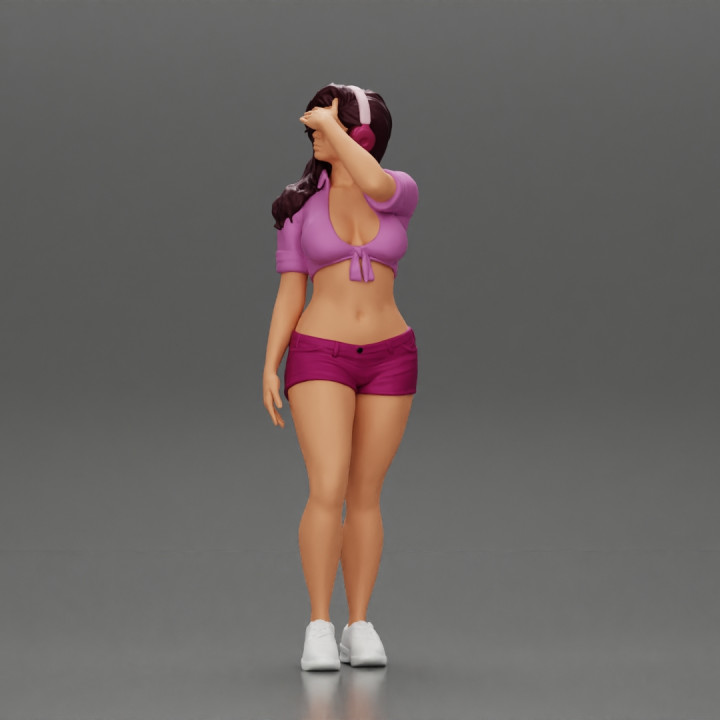 young woman in shorts and headphones shields her eyes from the sunlight