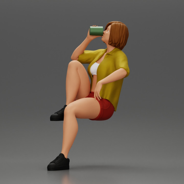 Young woman sitting on a chair hugging her pulled-up leg while drinking image