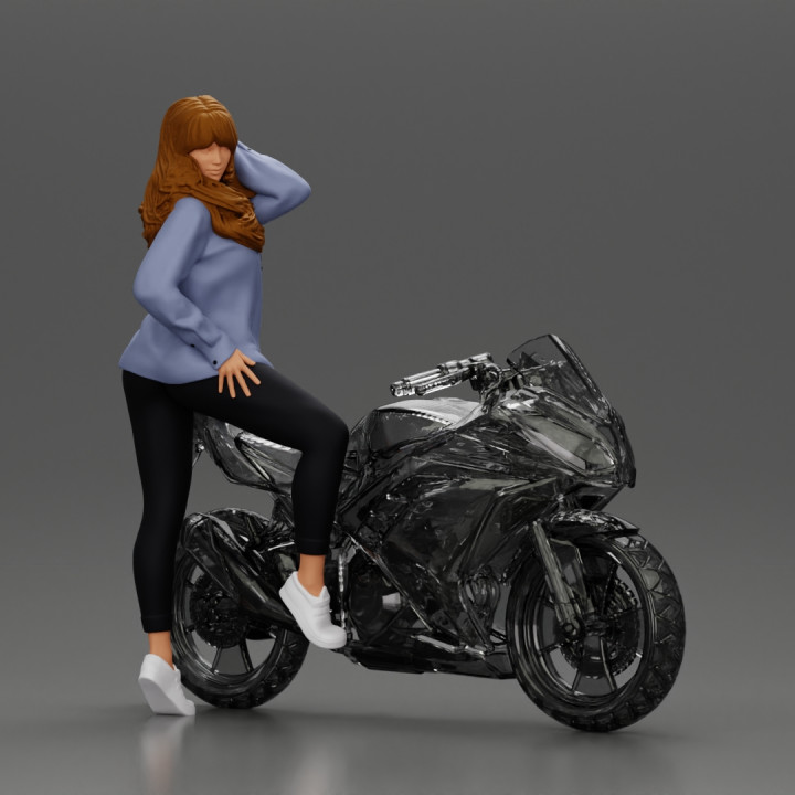 Young woman in  shirt with long hair posing with one foot resting on the motorcycle image