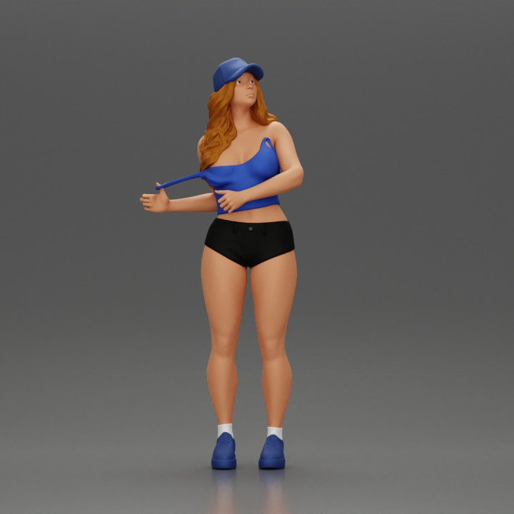 sexy girl standing in shorts and cap pulling off her bra image